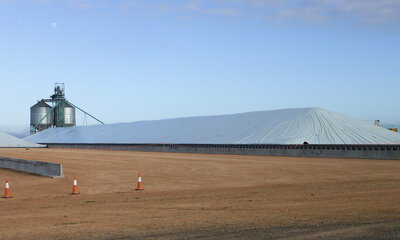 A large covered grain bunker. Two grain silos are behind it.