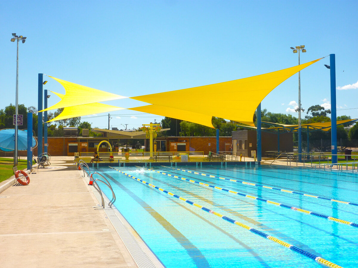 Yellow shade sails cover a swimming pool