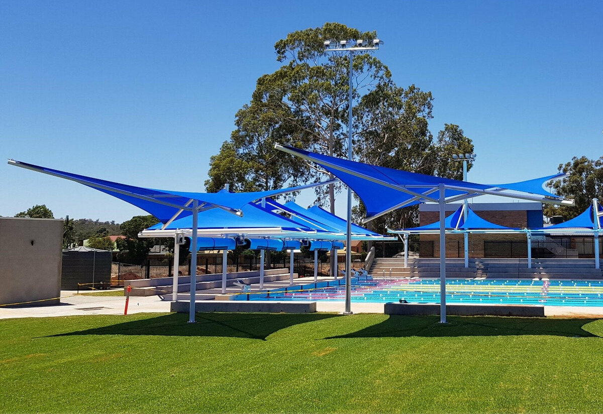 blue star structure shade sails cover seats around a swimming pool