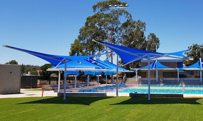 blue star structure shade sails cover seats around a swimming pool