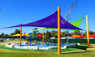 Pool covered by different coloured hypar shade sails.