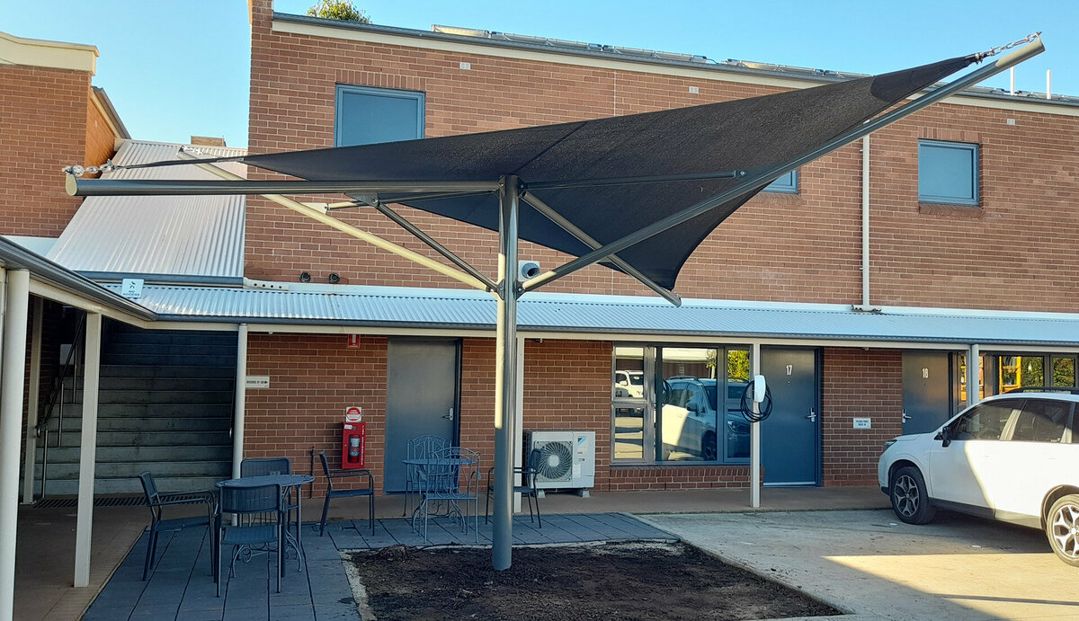 A blue shade sail covering a courtyard outside a brick building