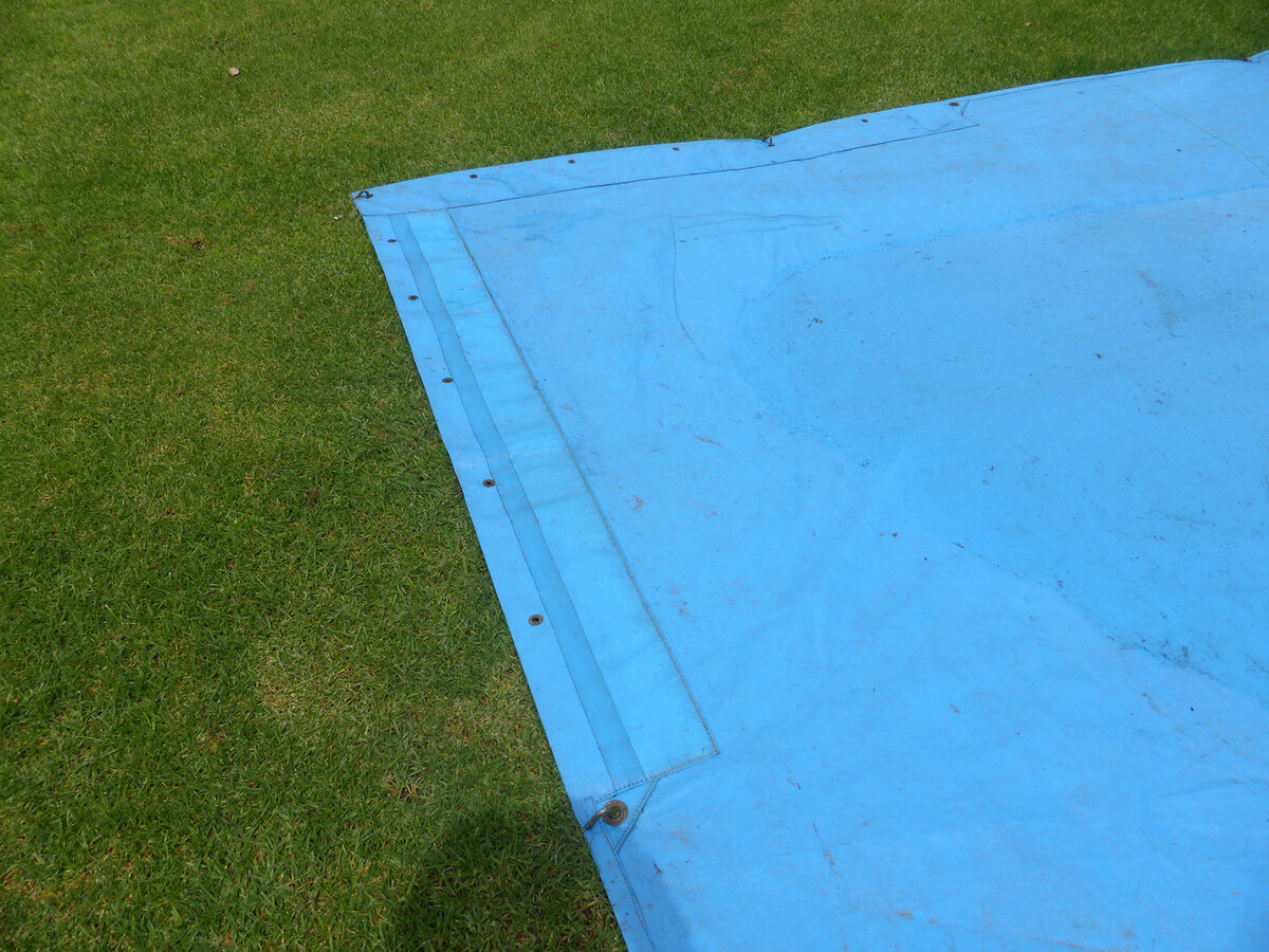 Corner of a blue cricket pitch cover on the grass