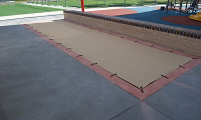 Sand pit at a playground covered with a mesh shade cloth