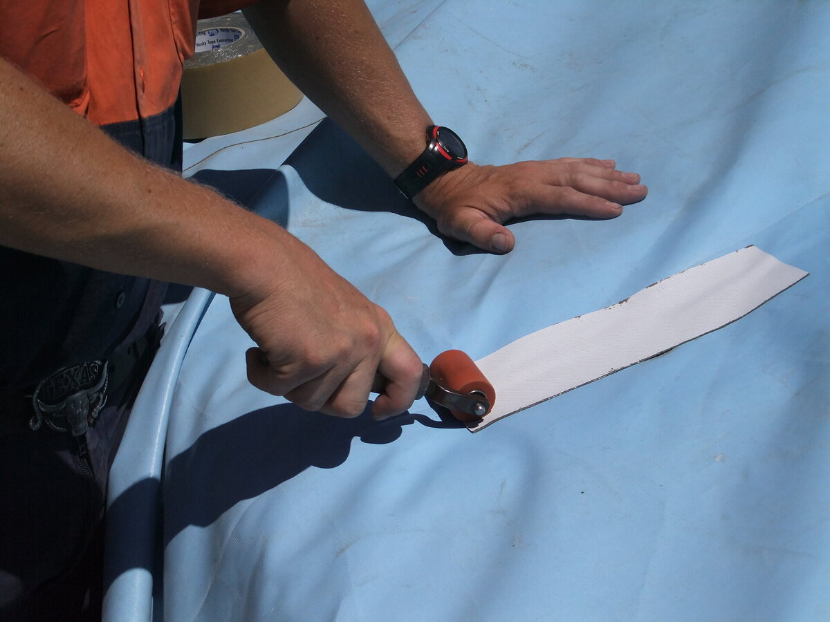 A tarp repaired using butyl tape and a silicon pressure roller.
