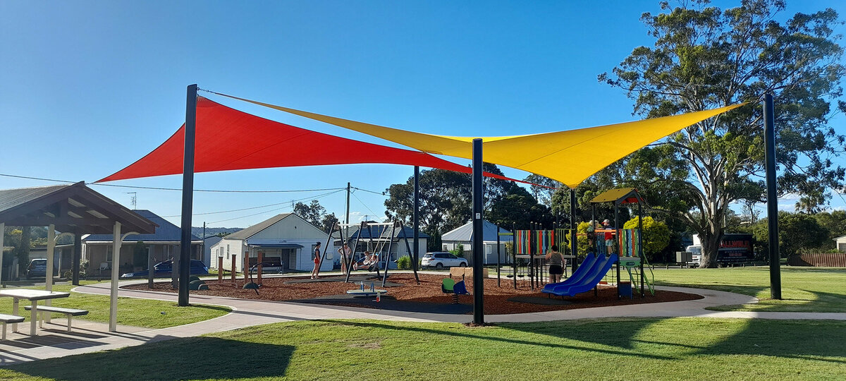 Red and yellow shade sails cover a playground