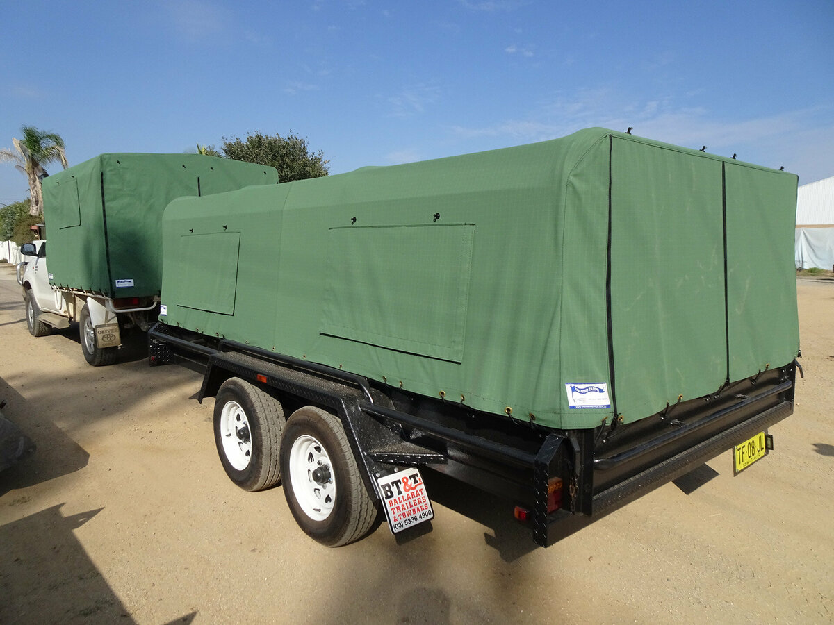 A ute carrying a trailer. The Ute tray and trailer both have green canvas covers attached