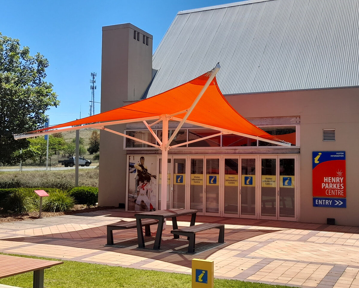 A red umbrella structure covers a picnic table in the Parkes visitor centre courtyard