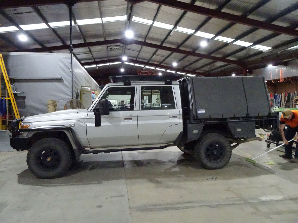 A ute in a large warehouse. It has a grey canopy covering the tray